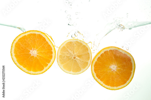 Three orange slices splash of water on white