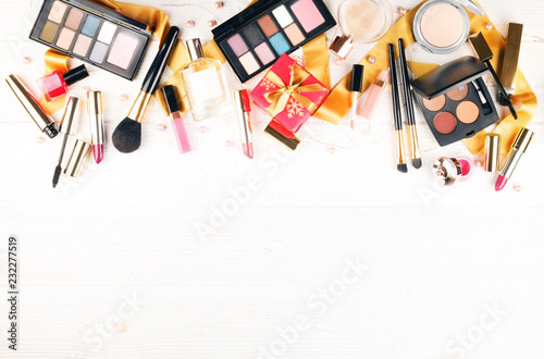Set of professional decorative cosmetics items, makeup tools and accessories on grunged concrete backgground. Beauty & fashion present for Christmas concept. Flat lay composition, top view, copy space