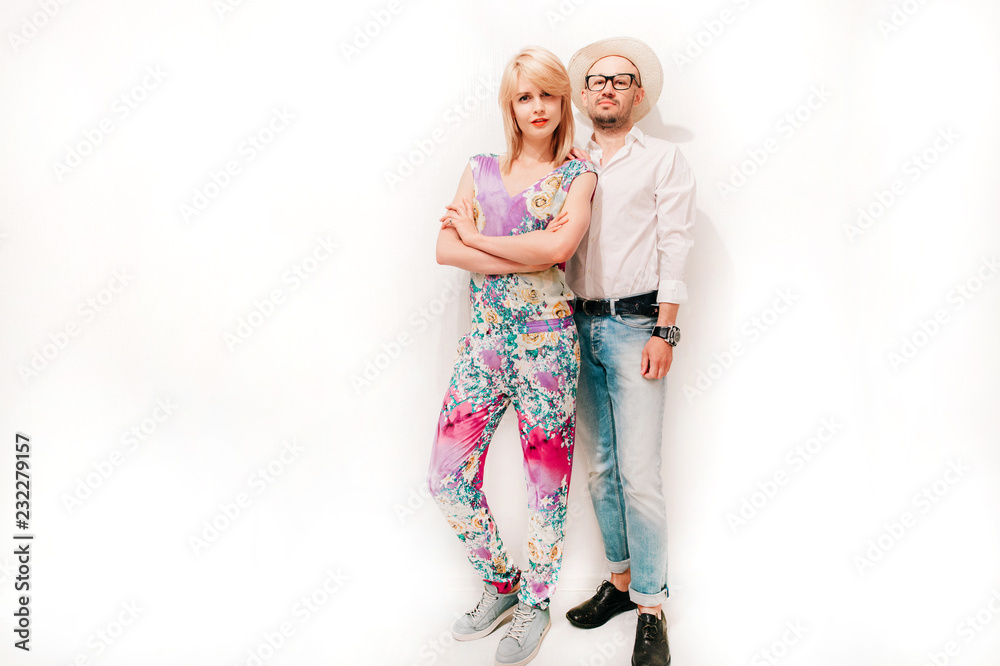Loving fashionable couple in trendy clothes hugging indoor. Young pair of lovers isolated on white wall lifestyle portrait. Nice looking friends posing together. Boy with girl. Odd beautiful people. Loving fashionable couple in trendy clothes hugging indoor. Young pair of lovers isolated on white wall lifestyle portrait. Nice looking friends posing together. Boy with girl. Odd beautiful people.