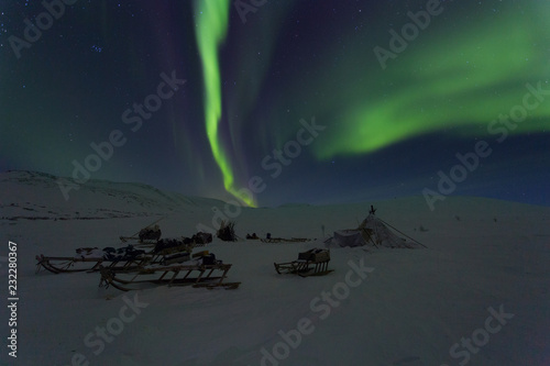 Winter night landscape with sledges, choom and aurora in the sky. The Yamal Peninsula. Russia