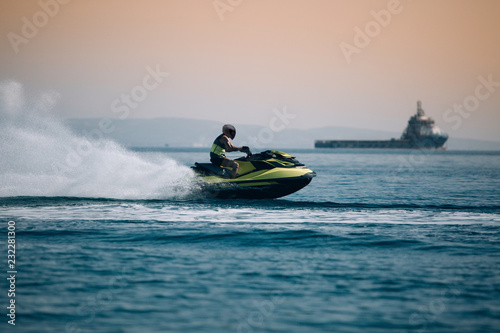 Man riding a jet ski at very high speed with spray behind. Powerboat go fast