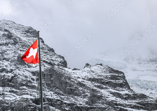 Prominent Waving Switzeland (swiss) Flag in a Snowy Mountain during a Winter Day