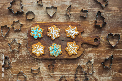 flat lay with christmas cookies on cutting board and cookie cutters around on wooden surface
