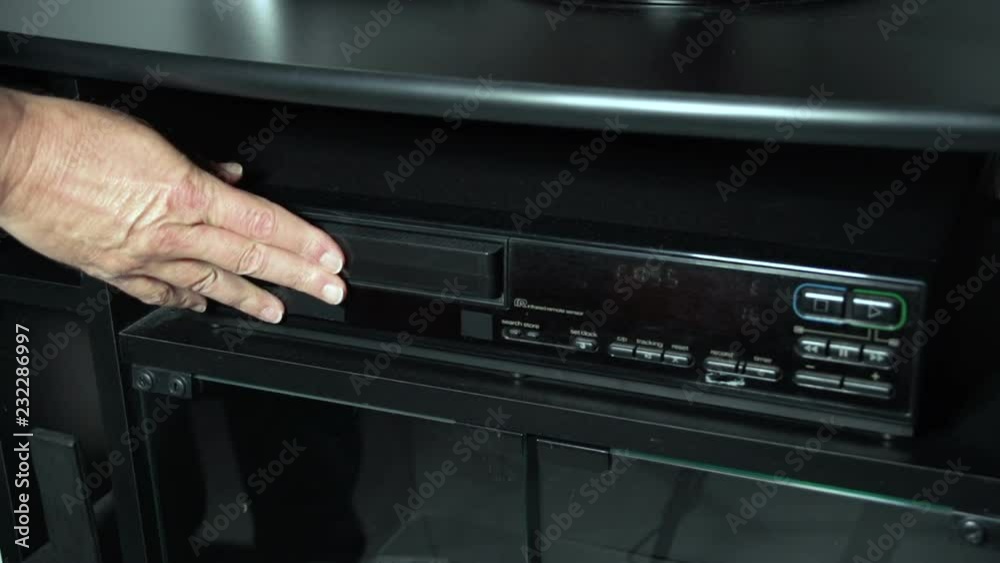 Hand of man starts a vhs tape in a vintage deck Hand of man starts a vhs tape in a vintage deck