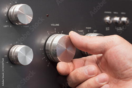 Hand turning up the volume in a stereo photo
