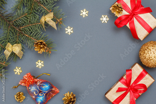Gift boxes, fir tree branches with cones and toys on gray background