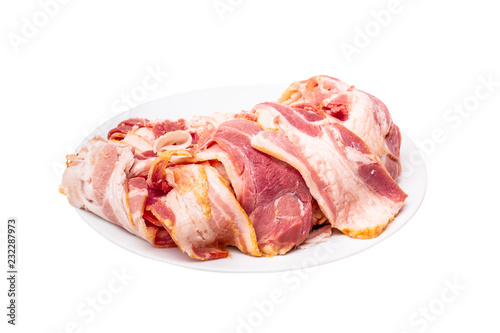 pile of raw bacon with plate isolated on white background with clipping path