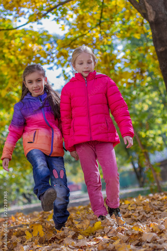 Two girls walking among autumn trees