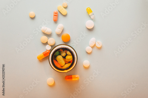 Multicolored isolated pills and capsules with a pillbox photo