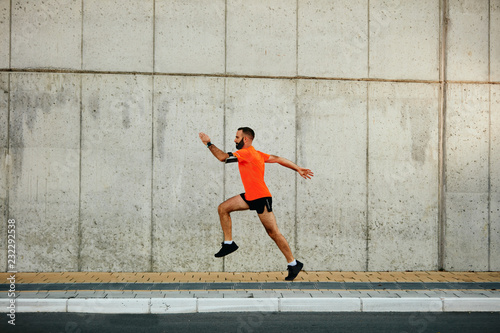 Young bearded man running on the street. Healthy lifestyle concept.