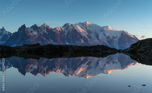 Panorama of the Mont Blanc massif reflected in Lac de Chesery during blue hour. Chamonix, France.