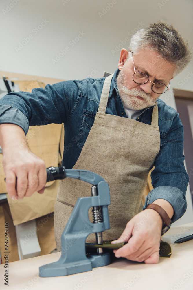 focused male handbag craftsman working with tool at studio focused male handbag craftsman working with tool at studio