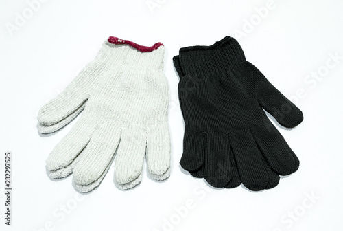 White and black cloth gloves for hand wear on white floor.