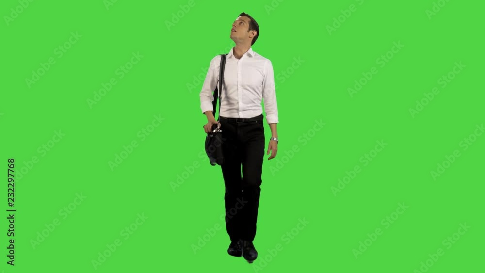 A young businessman walking relaxed towards camera in a full frontal shot, carrying a laptop, looking up amazed A young businessman walking relaxed towards camera in a full frontal shot, carrying a laptop, looking up amazed