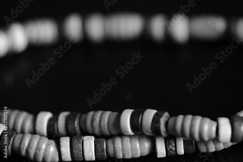 Fragment of a wooden necklace on a dark background close up. Black and white