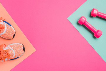 top view of sneakers and dumbbells on pink background
