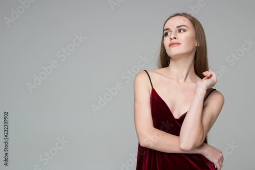Young blond girl in dark red dress showing emotions: satisfaction