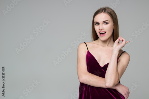 Young blond girl in dark red dress shows emotions: wonder