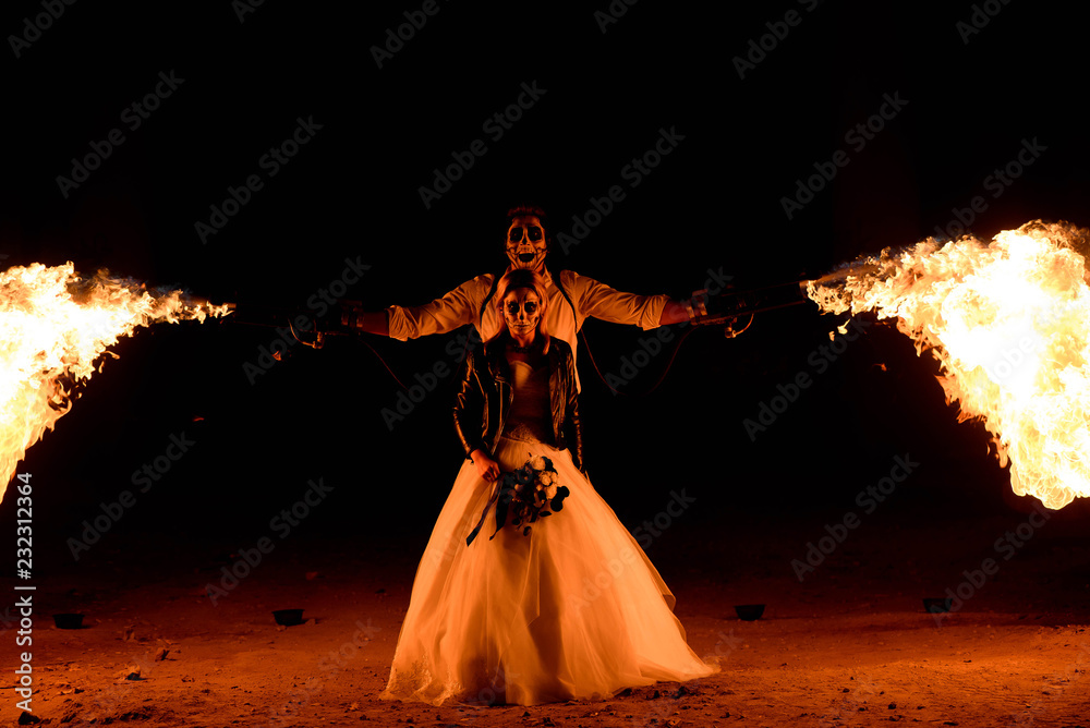 Halloween couple standing with flamethrower. big fire