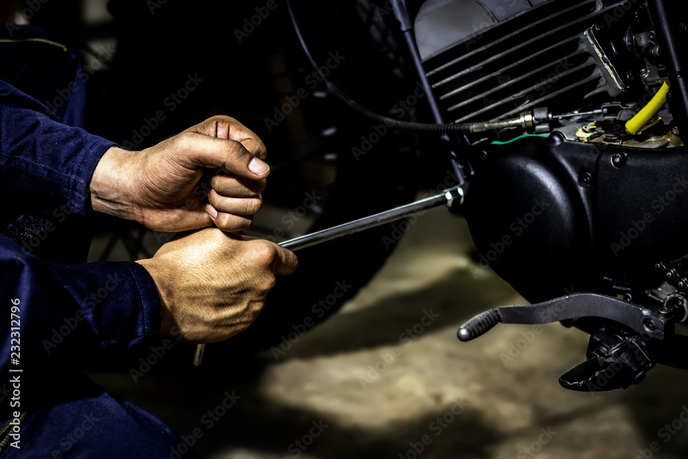 Obraz premium People use hand are repairing a motorcycle Use a wrench to work. Use the wrench to tighten the cylinder.