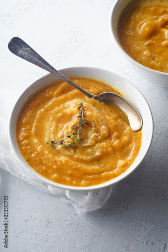 Pureed butternut squash soup with seeds and thyme. Warm food concept, dieting. Concrete background, side view.