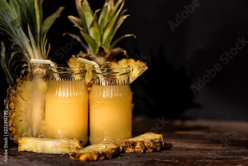 Pineapple juice and slice placed on a wooden table photo