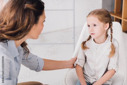 close-up shot of adult psychologist talking with little patient in office