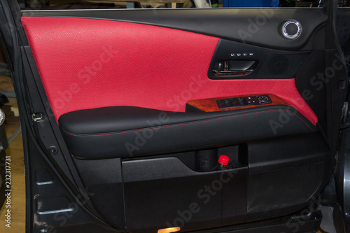 Interior of the SUV car with a rebuilt leather in red-black color in exchange for the old worn-out interior trim in the workshop for repairing the seat doors and steering wheels photo