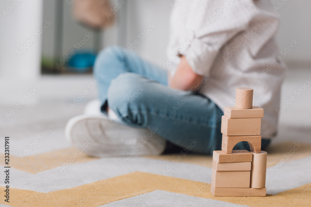 cropped shot of child sitting on floor with wooden blocks cropped shot of child sitting on floor with wooden blocks