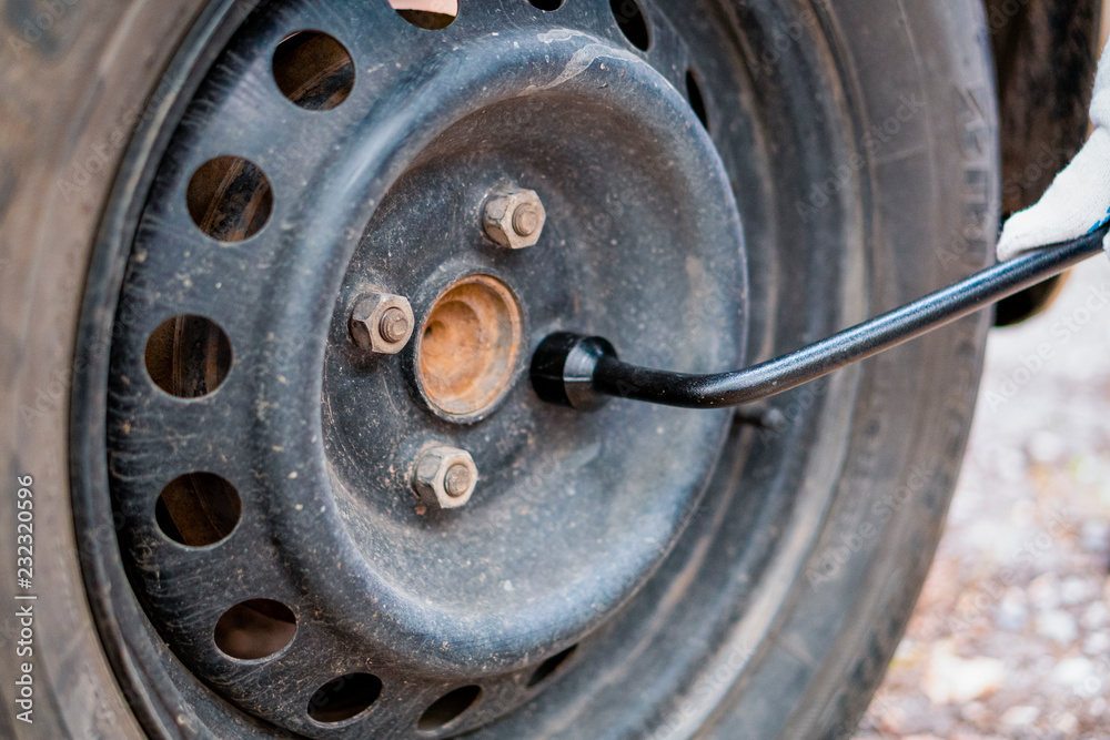 Tightening the nuts on the wheel of the car. Socket wrench.