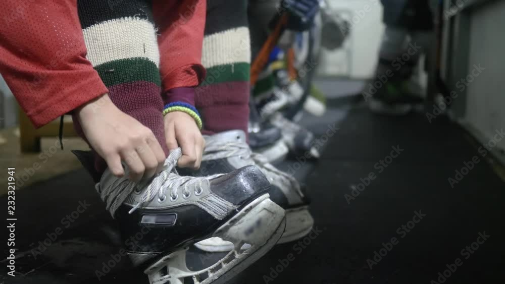 hockey player tying shoelace on skating and ready to go on rink, close-up on unfocused background