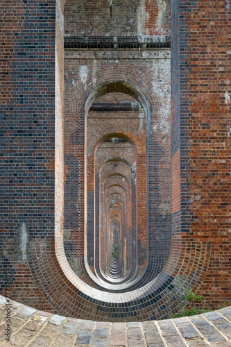 Looking through the arches of the Ouse Valley Viaduct near Haywards Heath, Sussex, UK. The viaduct is along the mainline from London to Brighton.  photo