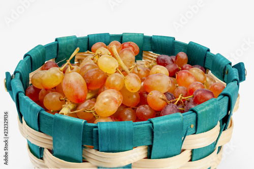 Grapes with small berries in a basket on a white background.