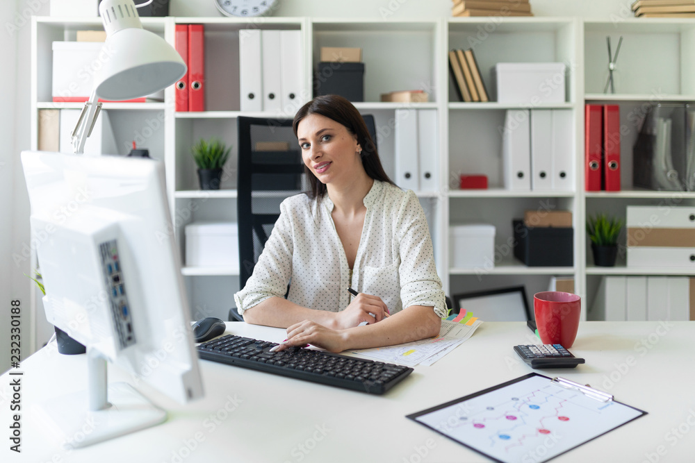 A young girl working in the office with documents and a computer. Portrait of a young girl at the table. A young girl working in the office with documents and a computer. Portrait of a young girl at the table.