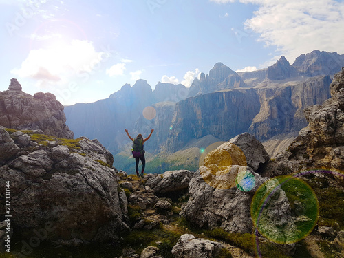 successful woman backpacker hiking on mountain peak and enjoying the view in the alps in the sunlight.