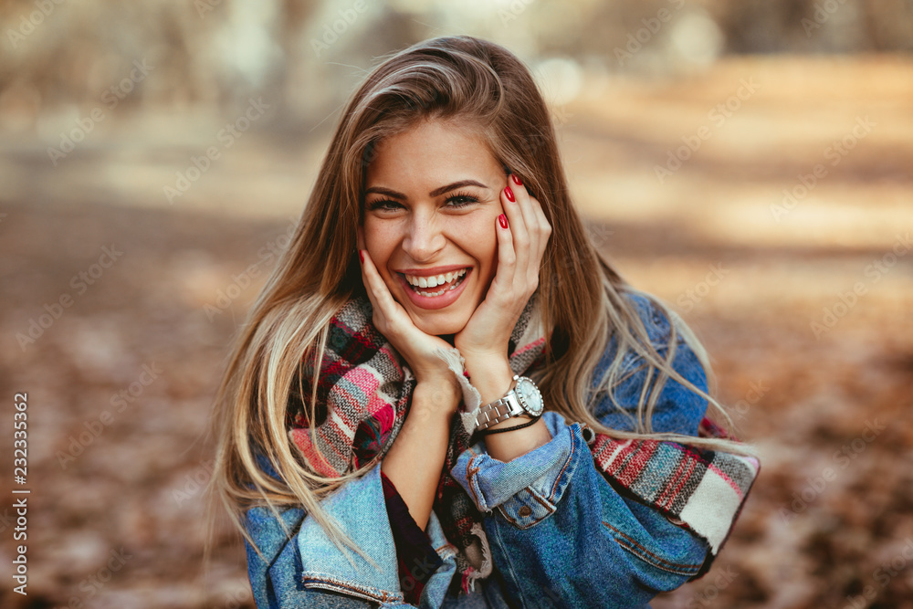 Fototapeta premium Portret piękna blondynka z uśmiechem na twarzy w parku