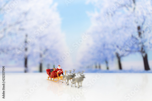 Miniature Santa Claus drive a wagon with a reindeer during the snowfall. Using as concept in Christmas day.