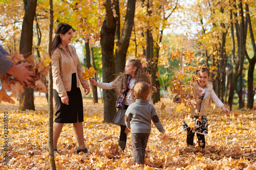 Happy family is in autumn city park. Children and parents. They posing, smiling, playing and having fun. Bright yellow trees.