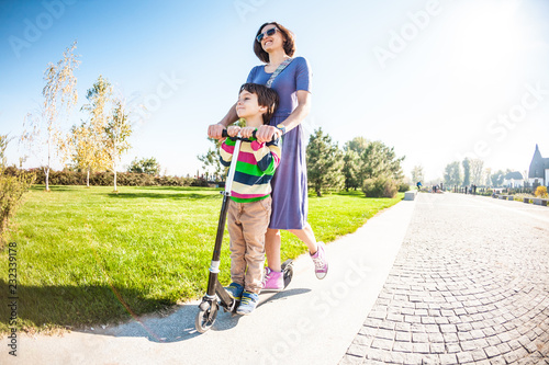 Woman riding with her son on a scooter.
