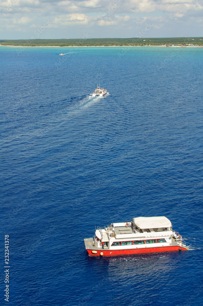 Three red and white sea boats carrying passengers from the liner to the shore. Cloudy sky, green tropical island and blue ocean. Aerial view Three red and white sea boats carrying passengers from the liner to the shore. Cloudy sky, green tropical island and blue ocean. Aerial view