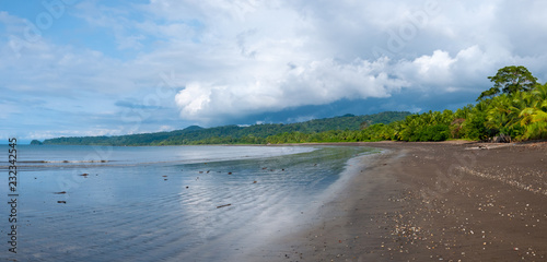 Beach landscape with black sand and tropical forest on a sunny day on the pacific coast of Colombia