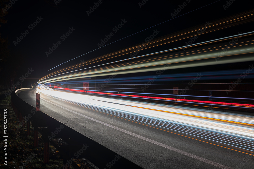 Lichtspuren vorbeifahrender Autos in der Nacht auf einer deutschen Autobahn