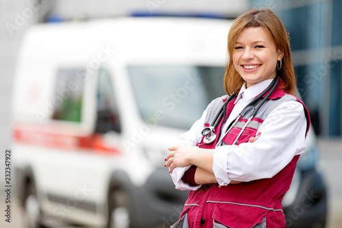 Medical concept. Happy paramedic female with phonendoscope at emergency car background photo