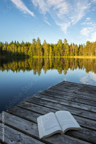 a book on a wooden pier on a lake