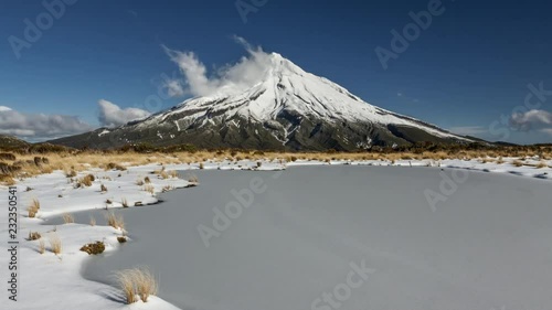 Volcano Mount Taranaki in New Zealand on clear winter day. Nice cloud forming on the snowy peak of the mountain. Timelapse video.