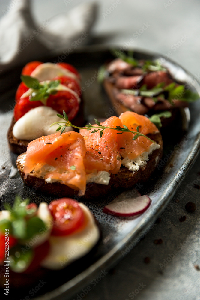 Sandwiches with roast beef and arugula, salmon and cumin, mozzarella and tomatoes on brown bread Sandwiches with roast beef and arugula, salmon and cumin, mozzarella and tomatoes on brown bread