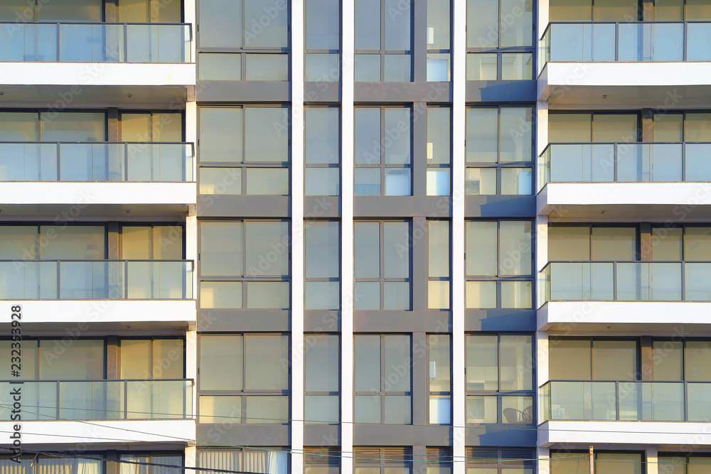Glass grey square Windows of modern city business building skyscraper. Glass balconies in the building. Modern apartment buildings in new neighborhood. Windows of a building, texture. Glass grey square Windows of modern city business building skyscraper. Glass balconies in the building. Modern apartment buildings in new neighborhood. Windows of a building, texture.