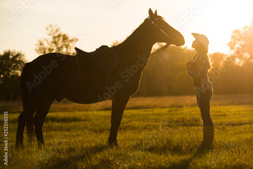 A girl rider stands near a horse and kisses a horse. Horse theme 