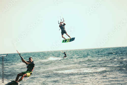 Professional kiter makes the difficult trick on a beautiful background. Kitesurfing Kiteboarding action photos man among waves quickly goes