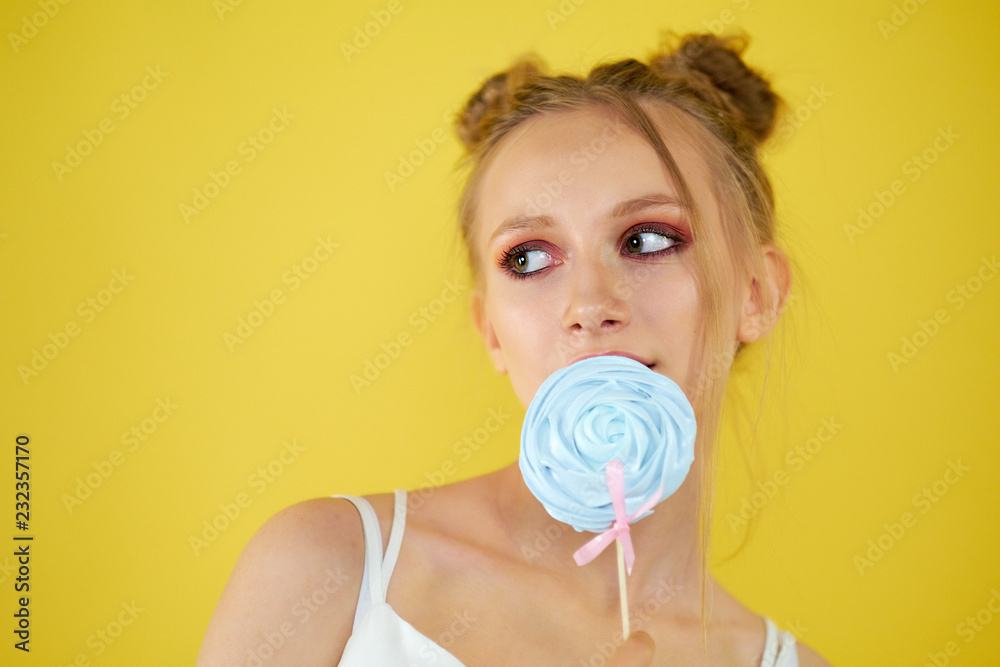 young girl with candy on a yellow bright background. beautiful make-up,